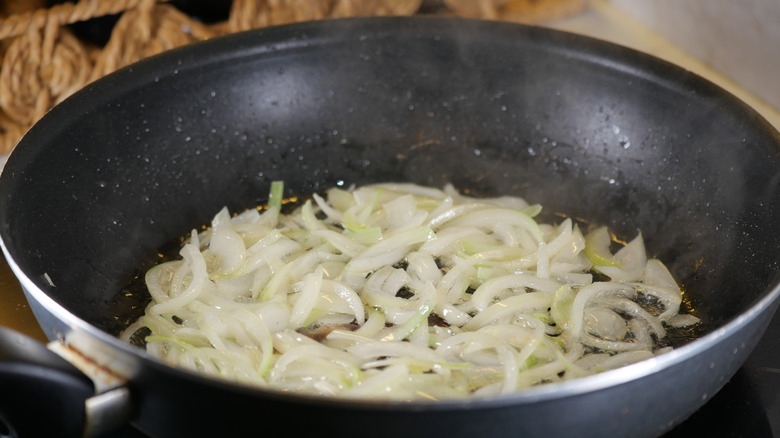Sliced onion strips in a deep frying pan.