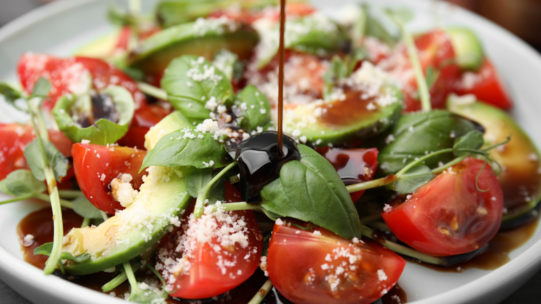 pouring a lot of balsamic vinegar onto a salad
