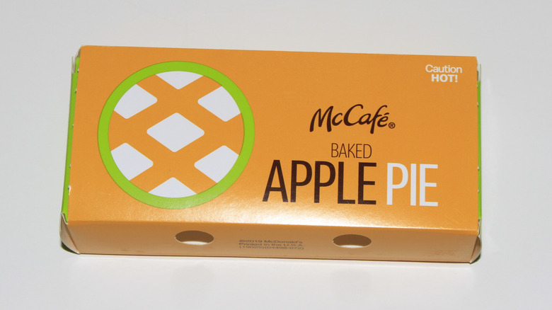 A McDonald's apple pie half out of the box on a wooden countertop