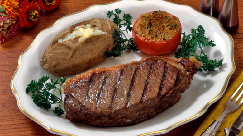 classic 1950s meal with huge steak and broiled tomato