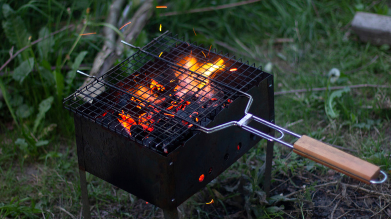 Person preheating grill with utensils