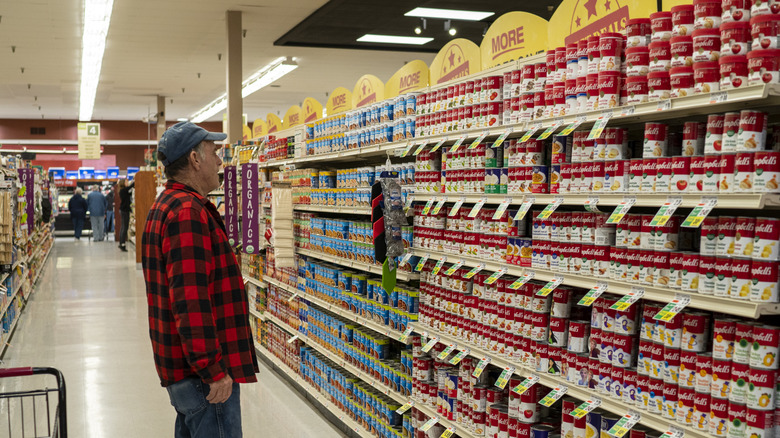 A man looking at supermarket display of canned soups