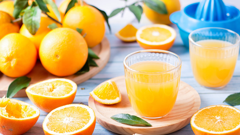 orange juice glass surrounded by oranges