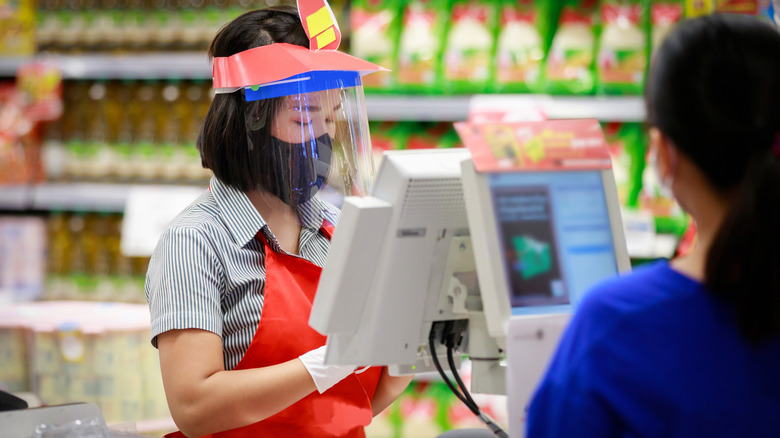 Grocery store clerk with face shield and gloves 