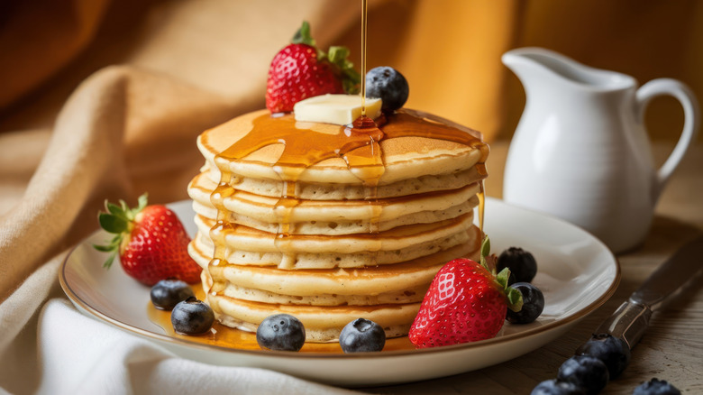 a stack of pancakes covered in syrup, butter, and fruit