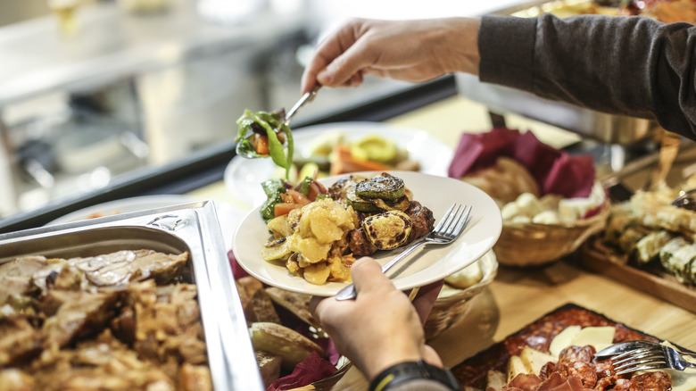 Person piling food on plate at buffet