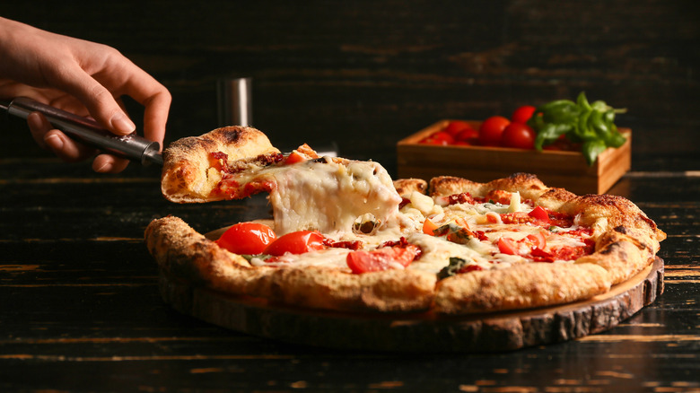 close up of person lifting slice of of pizza with spatula