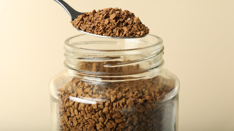 close up of spoonful of instant coffee on beige background