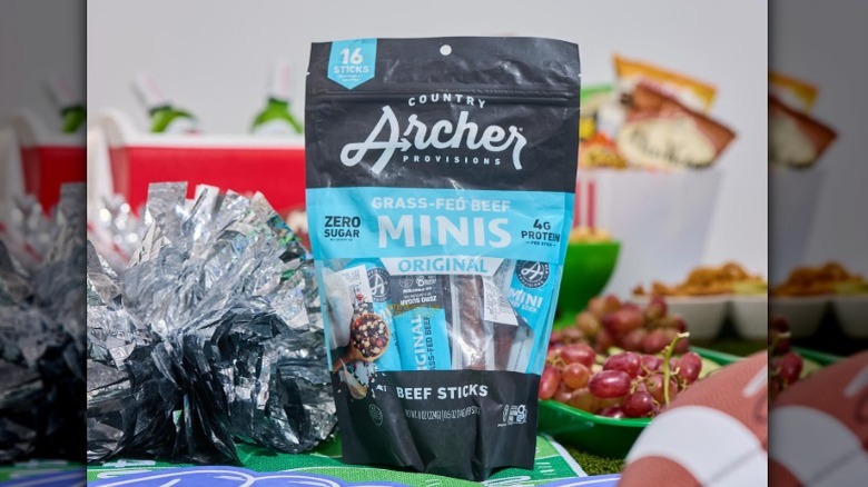 A bag of Country Archer Grass-Fed Beef Stick Minis on a crowded table