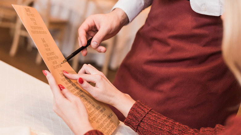 Customer pointing out something on the menu to the waiter
