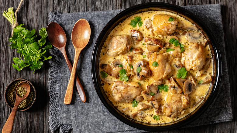 Chicken thighs, mushroom sauce, black bowl, wooden spoons