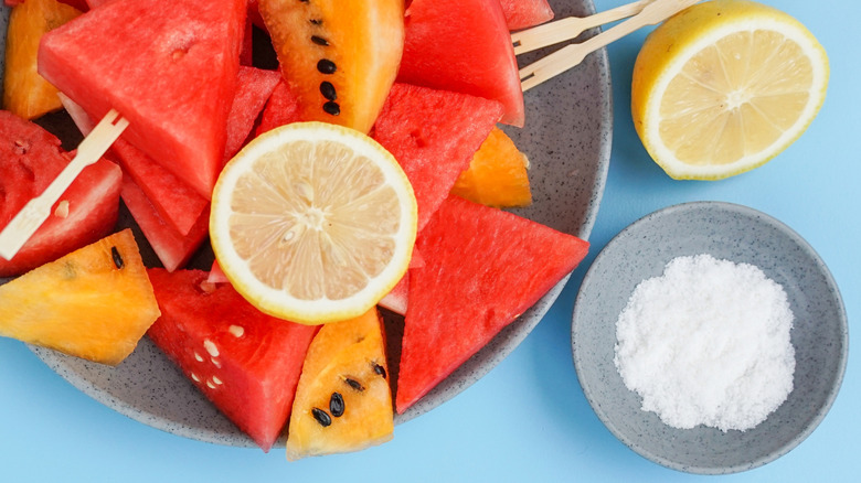 Tray of cut watermelon with lemon slices and a small dish of salt beside it