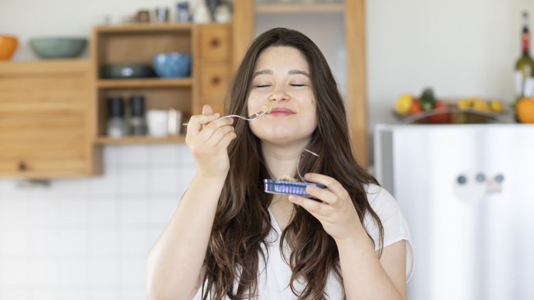 Woman eating from sardine tin
