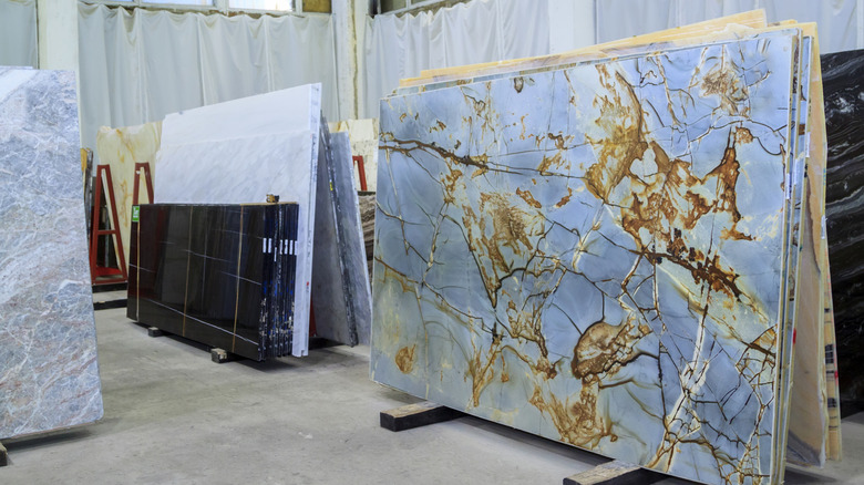 Slabs of marble on display including one that is pale blue with veins of black and rusty brown and orange