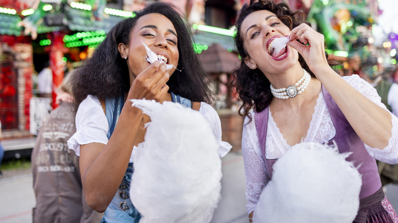 Women eating cotton candy at a carnival