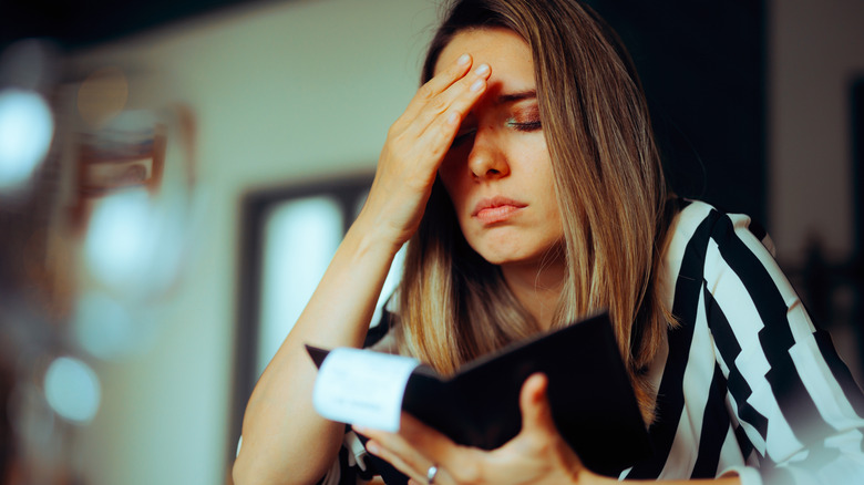 Woman with hand on head looking at restaurant bill