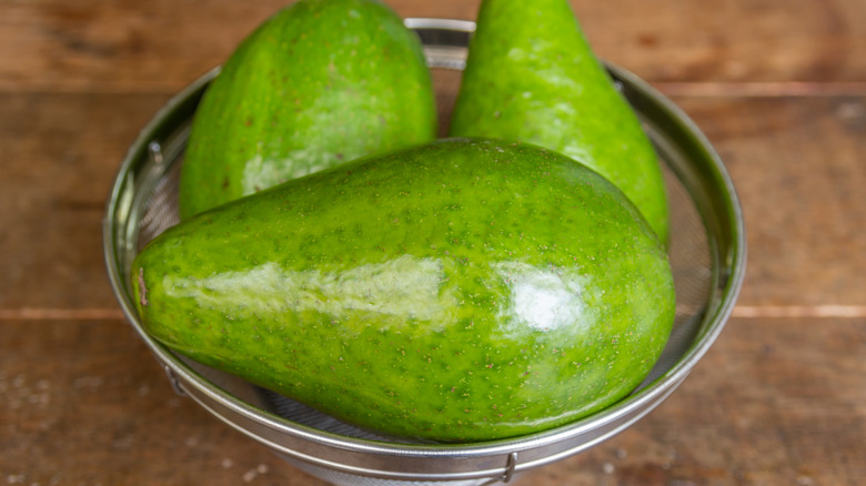 Bright green avocados in a metal bowl