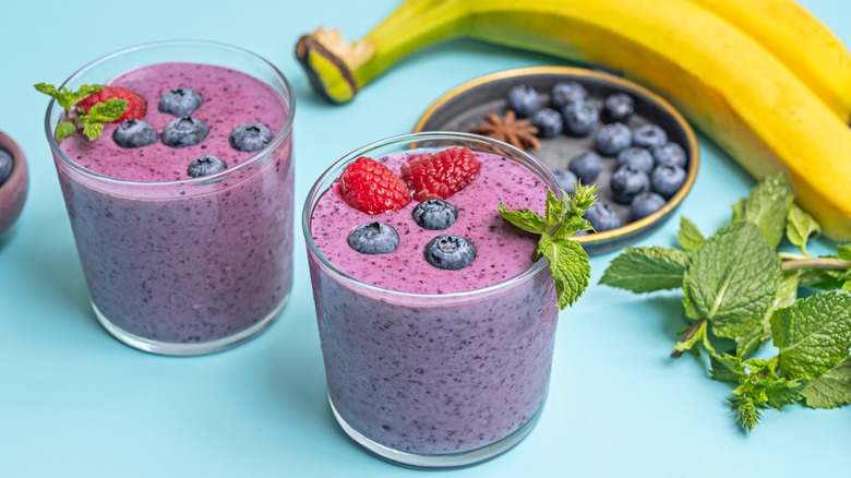 Breakfast smoothies with strawberries, blueberries, bananas, and mint leaves.