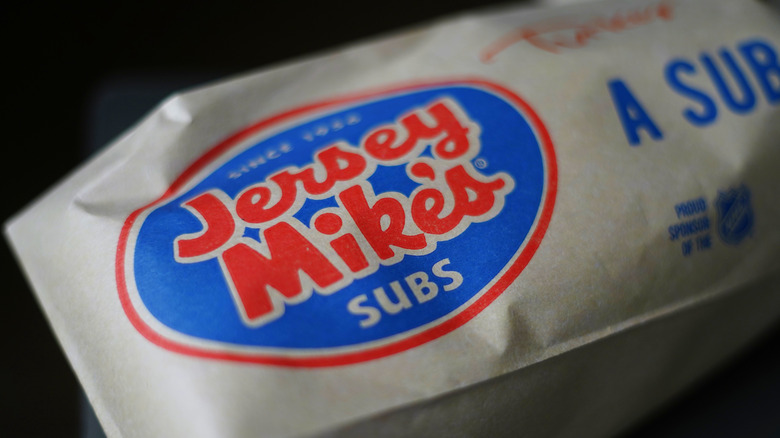 A Jersey Mike's sub wrapped in brown, logo-filled paper
