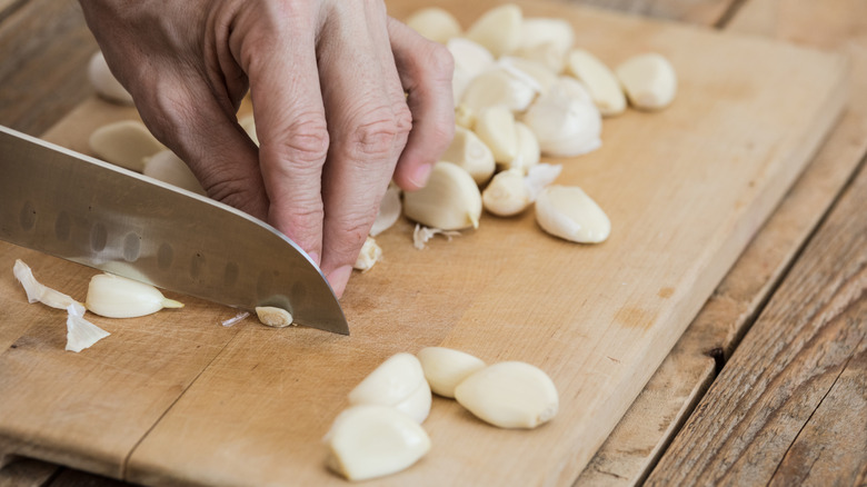 Someone cutting garlic with a Santoku knife