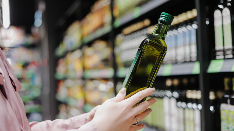 Woman selecting bottle of olive oil at the supermarket