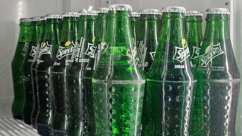 Green plastic bottles of Sprite lined up on a shelf