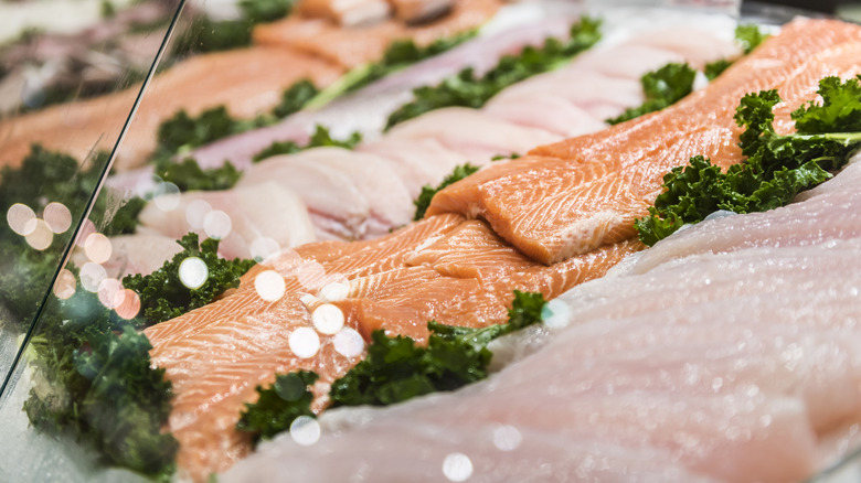 fresh seafood on display behind glass at a grocery store