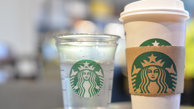 Starbucks hot drink next to a free cup of water