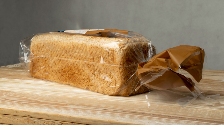 Loaf of sliced bread in plastic packaging sitting on wooden table