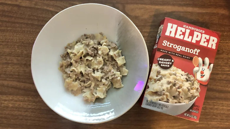 A bowl of Hamburger Helper stroganoff on a table next to the product's box
