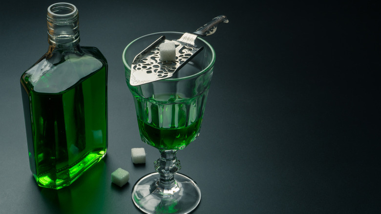 absinthe above glass with slotted spoon