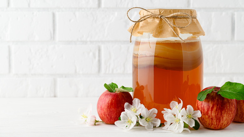 fresh kombucha surrounded by apples and white flowers