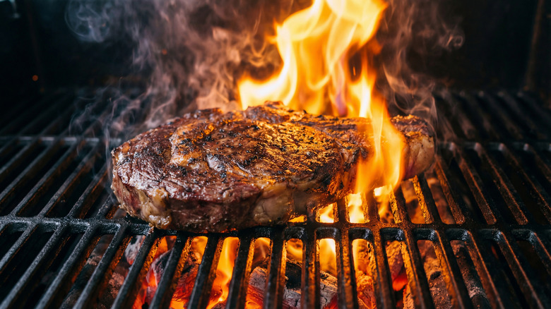 A steak grilling on a barbecue with fire