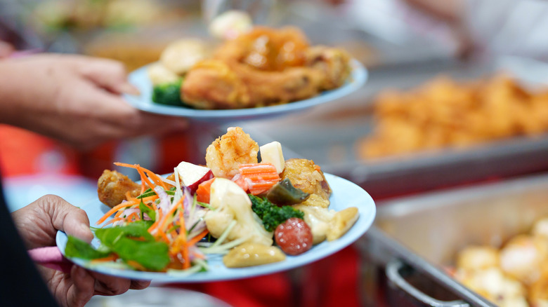 Two people carry their full buffet plates