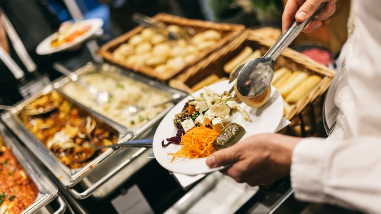 A person fills their buffet plate