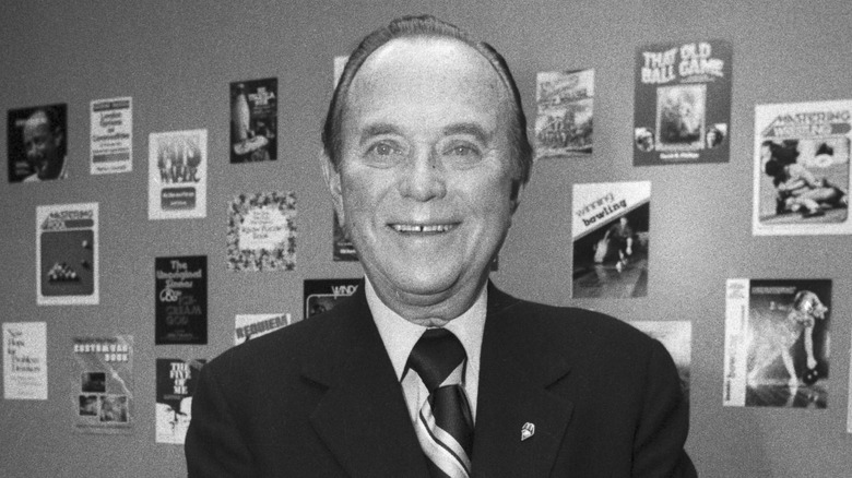 Ray Kroc smiles in front of a wall