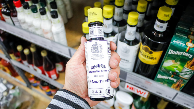 person holding Angostura bitters bottle in store