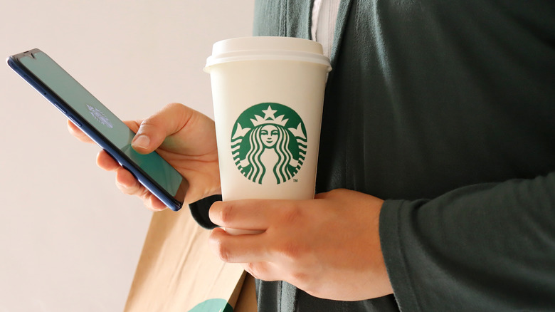 person with Starbucks cup opening app