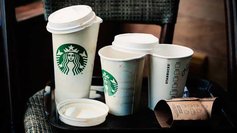 Messy Starbucks cups spilled on a tray, which is sitting on a chair