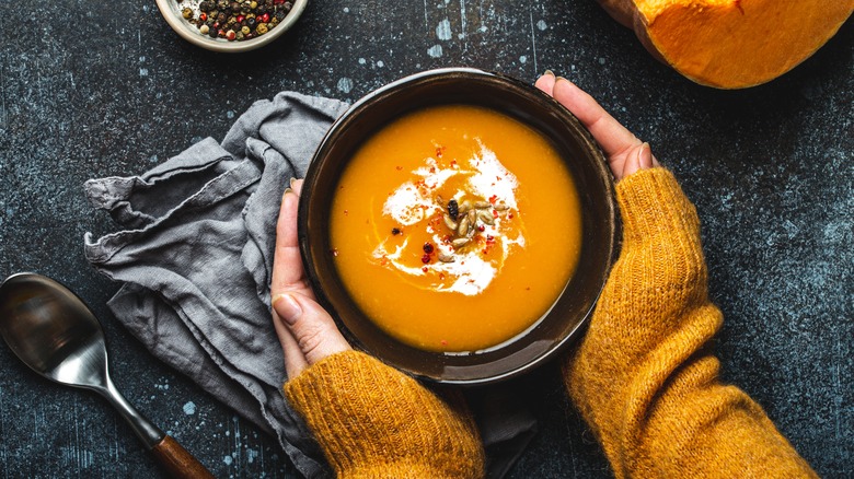 Hands holding bowl of soup