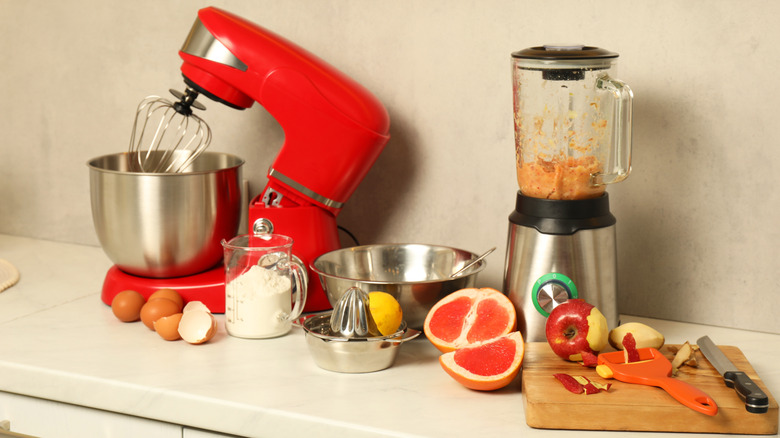 A red stand mixer and a blender on a kitchen counter with food and food prep items