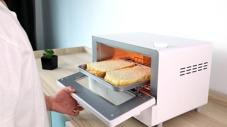 A person toasting bread in convection oven