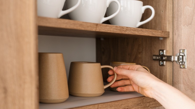 Home cook taking a mug out of a cabinet