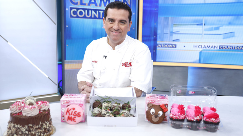Buddy Valastro sitting at a news desk, in front of him are various baked items deocrated for Valentine's Day