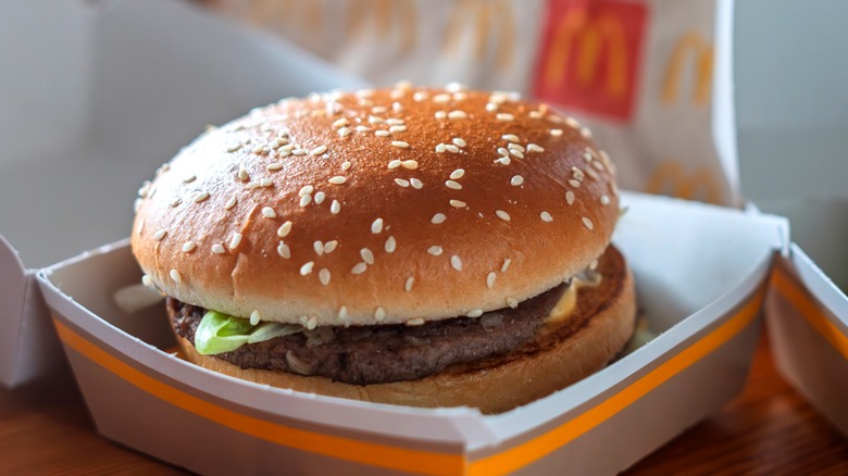 Hamburger on sesame seed bun from McDonald's inside beige cardboard burger box