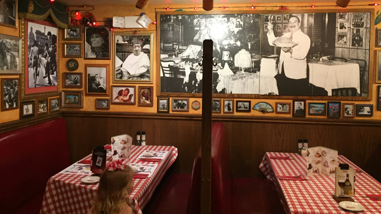Tables are set at Buca di Beppo, which has red checkered tablecloths and pictures of celebrities and others on the wall.