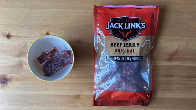 A bag and bowl of Jack Link's beef jerky on a wooden table.