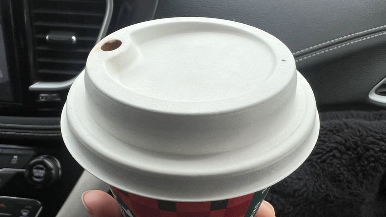 Someone holding a Starbucks cup in a car, focus on the white lid