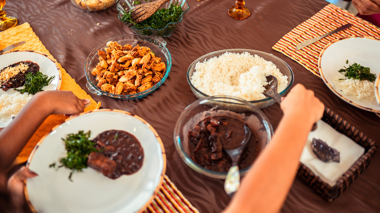 a person reaches for rice at a family-style dinner that included black beans