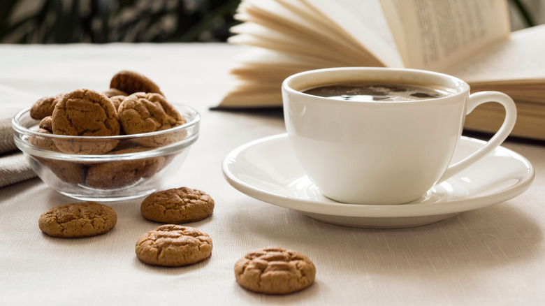 mug of coffee next to bowl of cookies